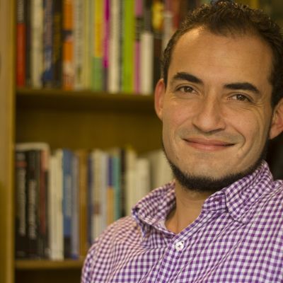 Juan Sebastian Rojas, Colombian man, smiling with bookcase in background